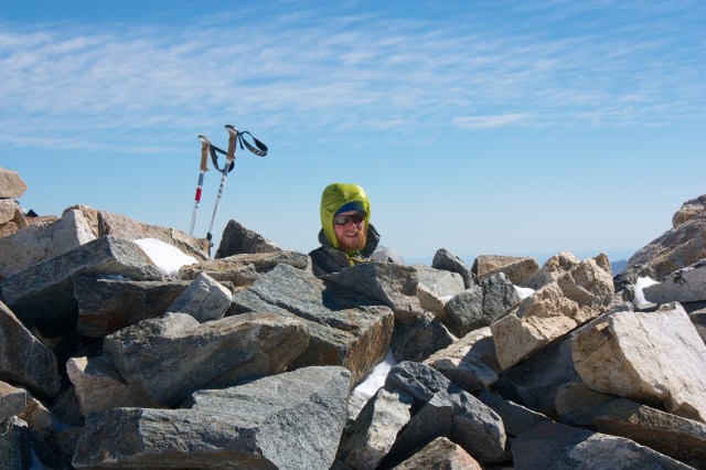 Junaid huddles behind some rocks to shelter from the wind while he sends out the SPOT from Gray's Peak.
